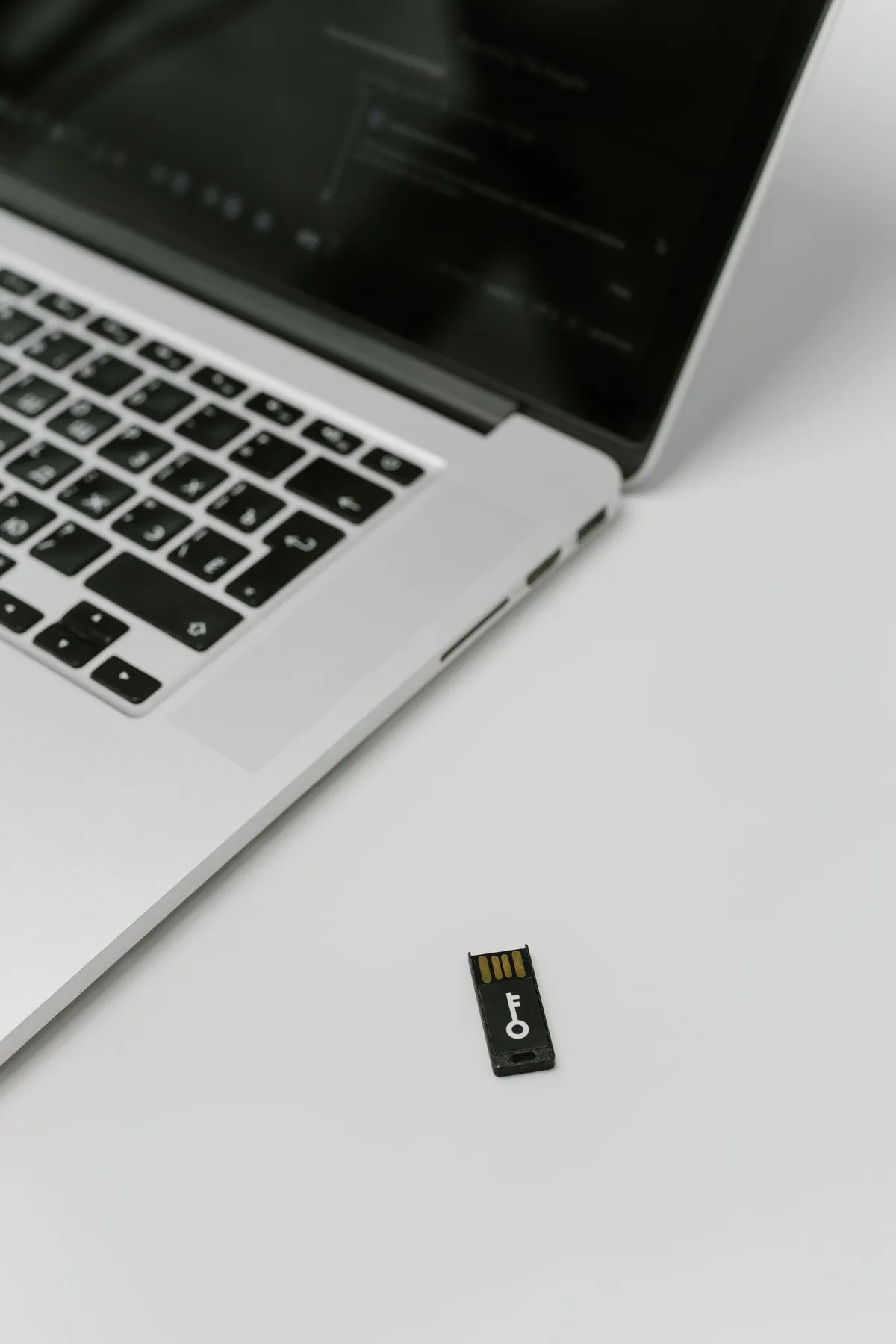 Two keyboard tiles and a hardware security key beside a laptop, representing site and secret API credentials